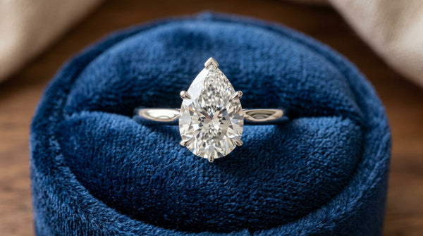 A close-up of a high-quality engagement ring teardrop shaped with protective V-tip prongs.