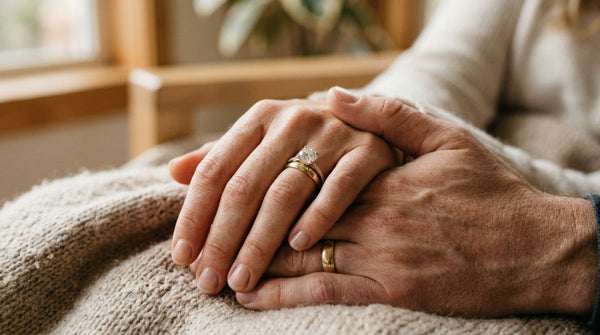 Close up photo of a couple holding hands showing a traditional diamond engagement ring and gold wedding band.